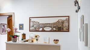 A reception desk with a framed black and white photograph of a bridge and buildings, a potted orchid, a small plant, and a bowl of dried flowers. - Antica Posta Bed & Breakfast - Florence (Florence)