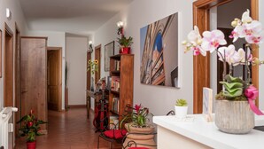 A hallway with a wooden door, a bookshelf, a potted plant, a guitar, and a painting on the wall. - Antica Posta Bed & Breakfast - Florence (Florence)