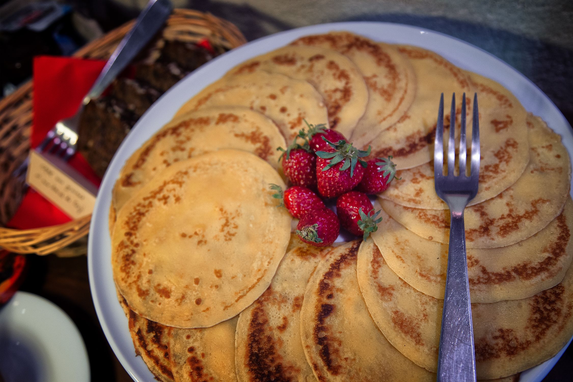Una pila de tortitas con fresas y un tenedor.