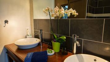 A bathroom with two sinks, a mirror, a towel, and a potted orchid.