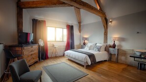 A bedroom with a bed, a desk with a TV, a chair, a lamp, and a window with curtains. - Le Chai de la Paleine (Le Puy-Notre-Dame)