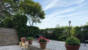 A garden with potted plants, a stone wall, and a lamp post. - Villa Porta all'Arco (Volterra)