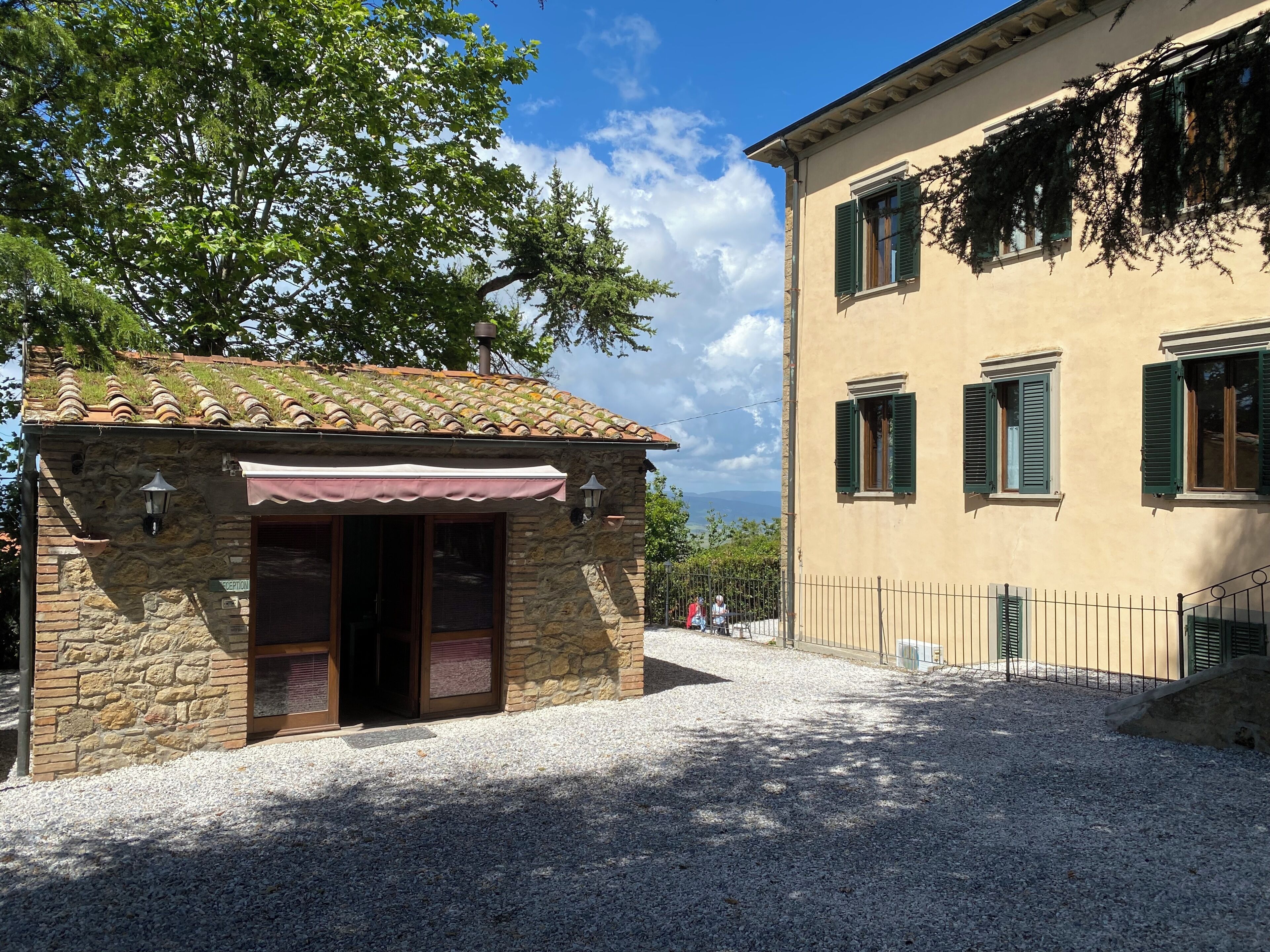 A stone building with a tiled roof and a gravel courtyard.