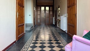 A hallway with checkered flooring, wooden doors, and a radiator. - Villa Porta all'Arco (Volterra)