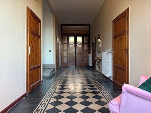 A hallway with checkered flooring, wooden doors, and a radiator. - Villa Porta all'Arco (Volterra)