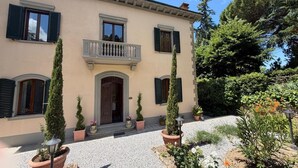 A two-story building with a balcony, potted plants, and a gravel driveway. - Villa Porta all'Arco (Volterra)