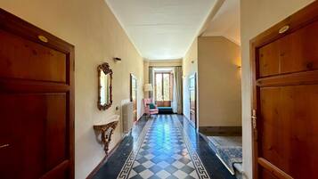 A hallway with checkered flooring, wooden doors, a mirror, and a bench.