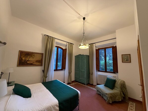 Un dormitorio con dos camas, un radiador, un armario verde y un cuadro en la pared.