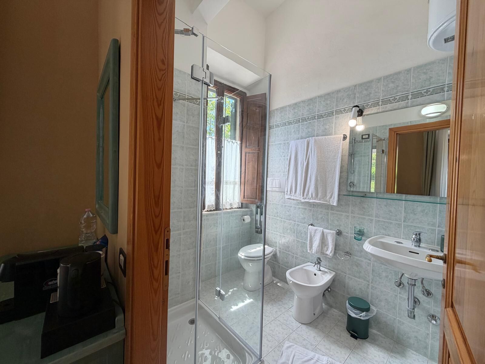 A bathroom with a glass shower enclosure, a toilet, a bidet, a sink, and a mirror.