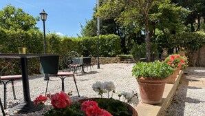 A garden patio with outdoor seating, potted plants, and a lamp post. - Villa Porta all'Arco (Volterra)