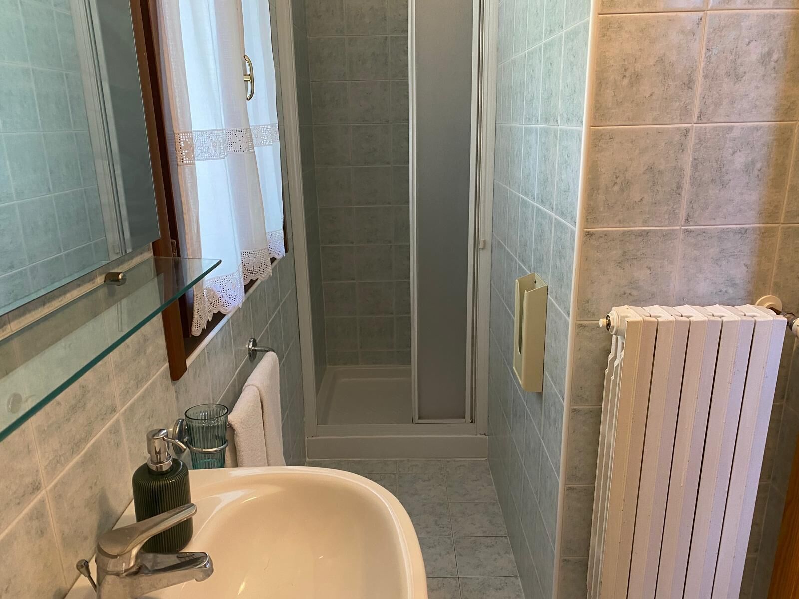 A bathroom with a glass shower enclosure, a sink with a faucet, and a towel rack.