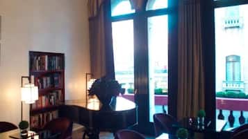 A hotel lobby with a chandelier, bookshelves, and large windows.