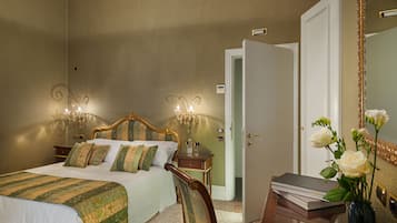 A bedroom with a bed, bedside tables, a mirror, and a vase with flowers.
