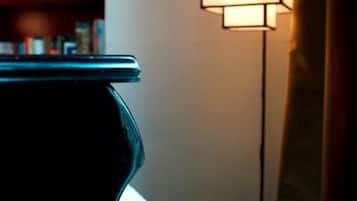 A piano in a dimly lit room with a bookshelf in the background.