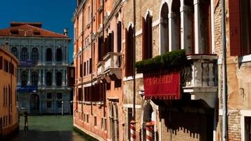 A canal-side building with a red awning, arched windows, and a brick facade.