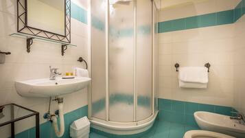 Une salle de bain avec une douche à parois de verre, un lavabo, un bidet et un miroir.