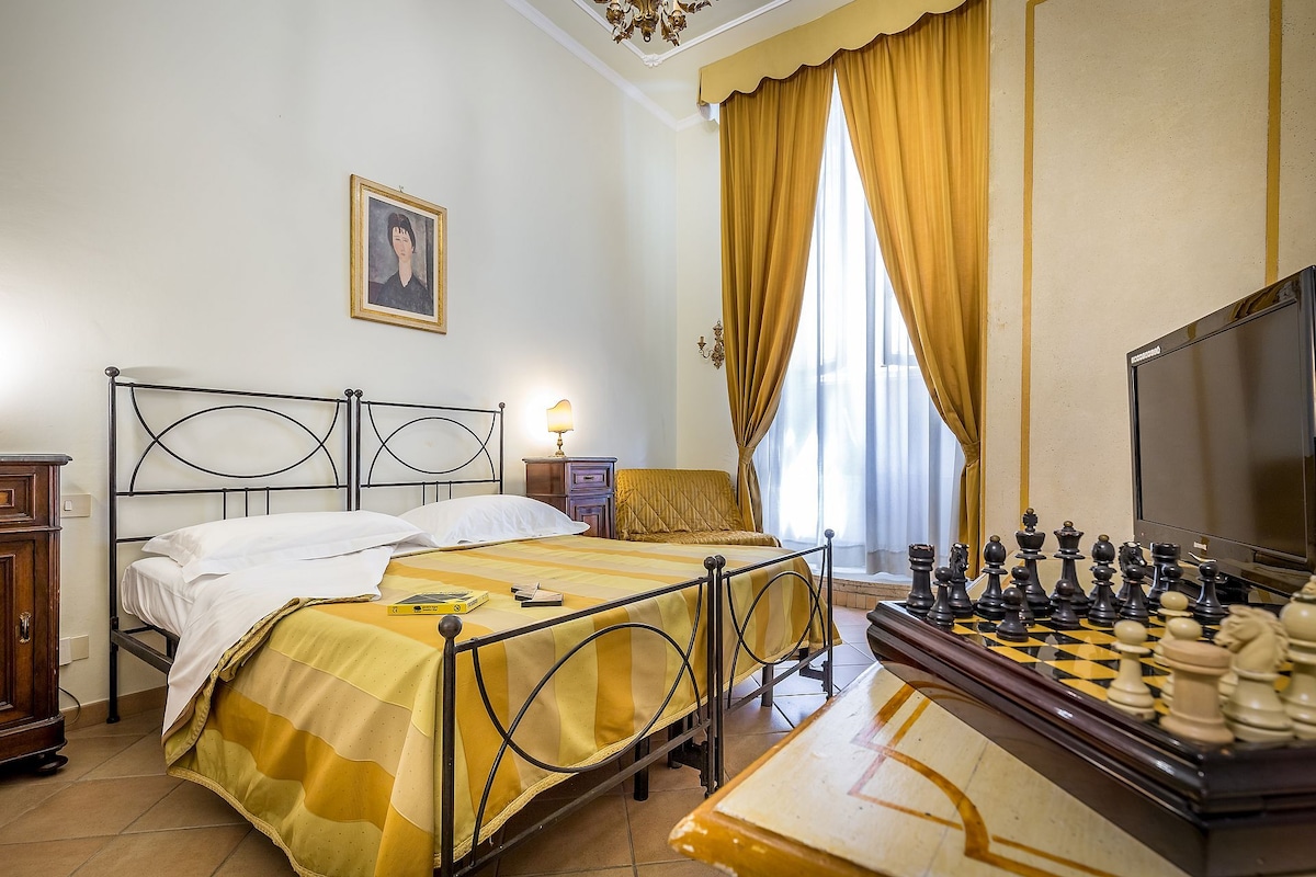 Une chambre d’hôtel avec un lit, un bureau doté d’une lampe, une chaise et un jeu d’échecs.