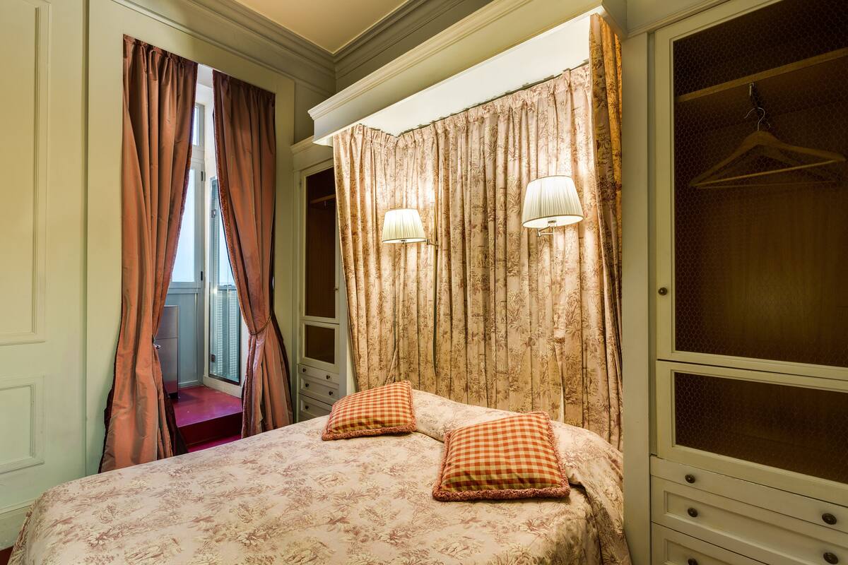 Un dormitorio con cama, dos almohadas, armario y ropero.