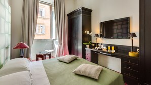 Habitación de hotel con cama, escritorio, televisor de pantalla plana, cómoda y ventana con cortinas.