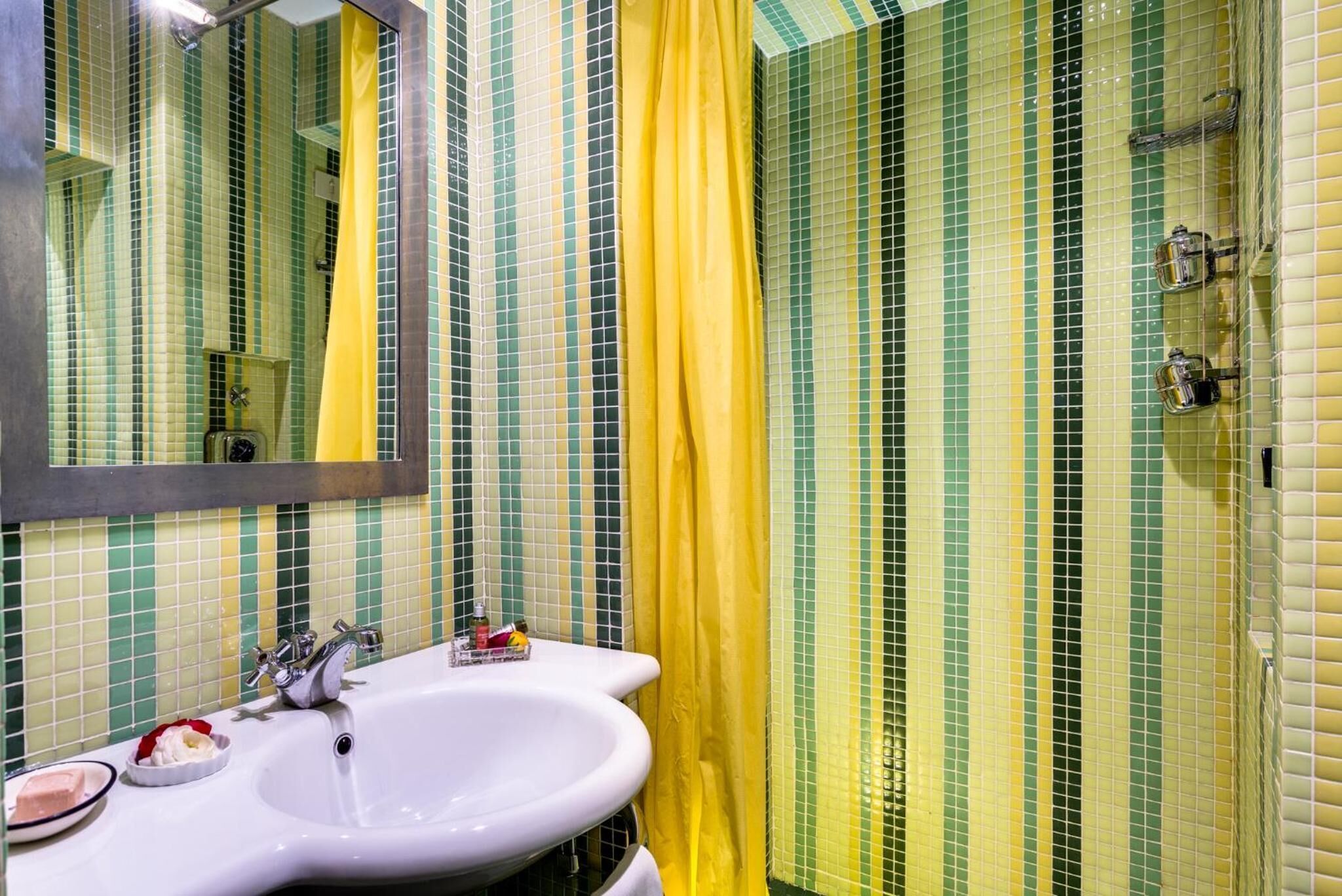 A bathroom with a white sink, a mirror, and a shower area with yellow curtains.