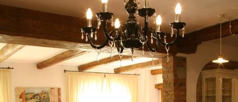 A dining area with a table set for breakfast, a chandelier, and a view of the kitchen.
