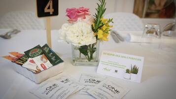 A hotel room with a bed, a small table with a number 4 sign, a vase with flowers, and hygiene products.