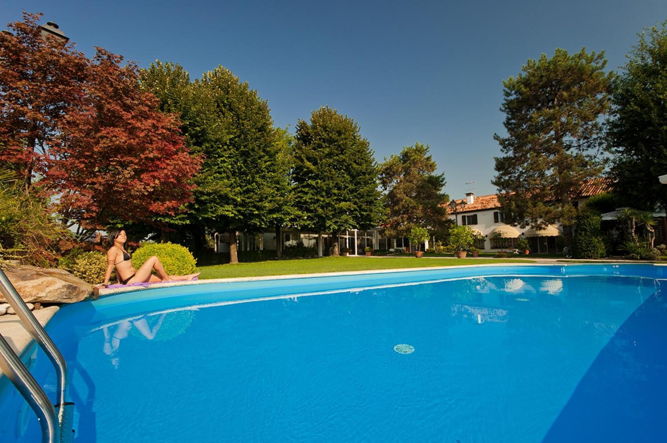 Een buitenzwembad, parasols bij het zwembad en ligstoelen