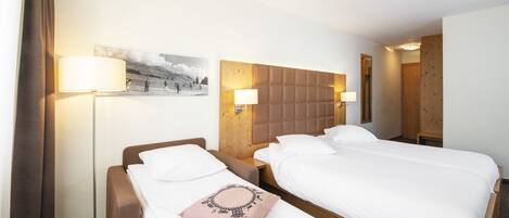 Habitación de hotel con dos camas, cabecero, lámparas de noche, un cuadro en la pared y una puerta de madera.