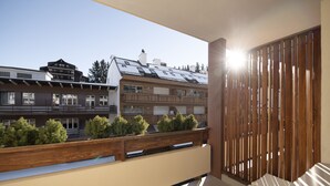A balcony with a wooden railing, a view of buildings, and a clear sky. - Olympic (Crans-Montana)