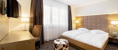 Une chambre d’hôtel avec un lit, un bureau, une chaise, une télévision et une lampe.