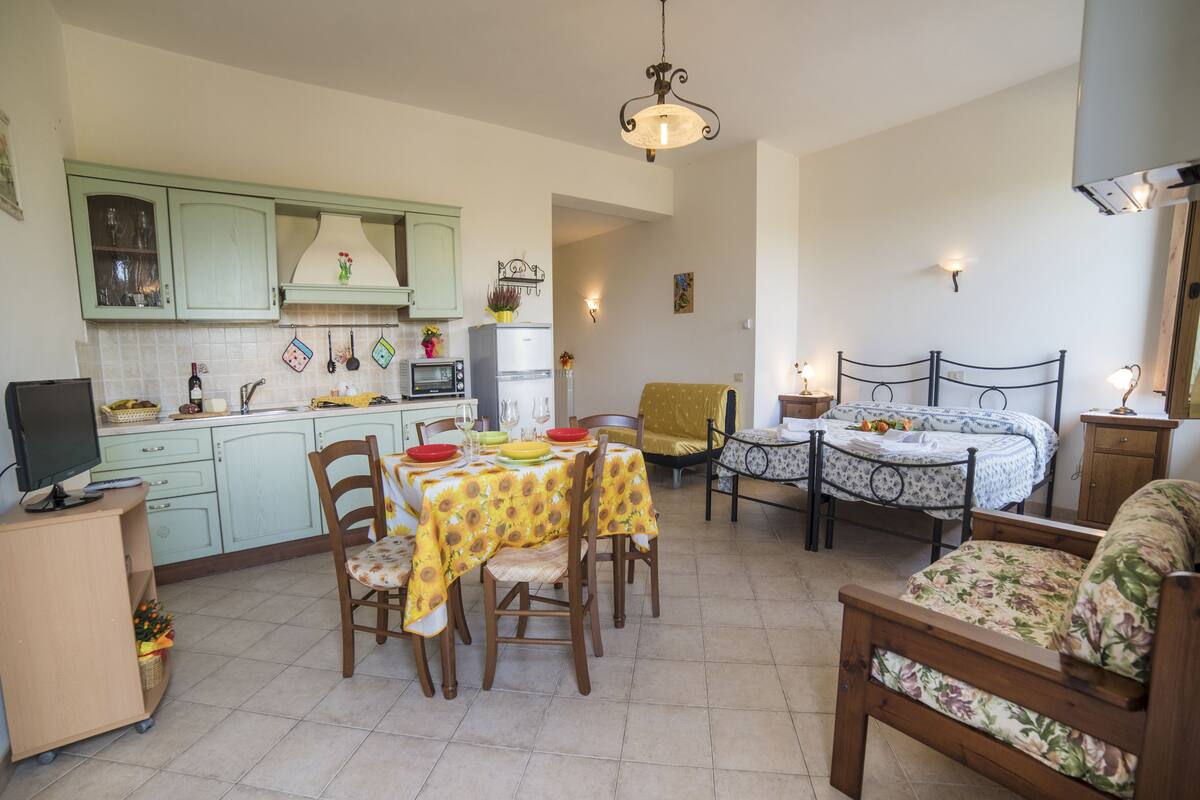 A compact living space with a dining area, kitchenette, and a bed.