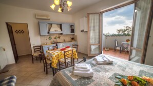 A compact kitchen with a dining table, chairs, and a balcony with a view. - Casa Santa Caterina (Asciano)
