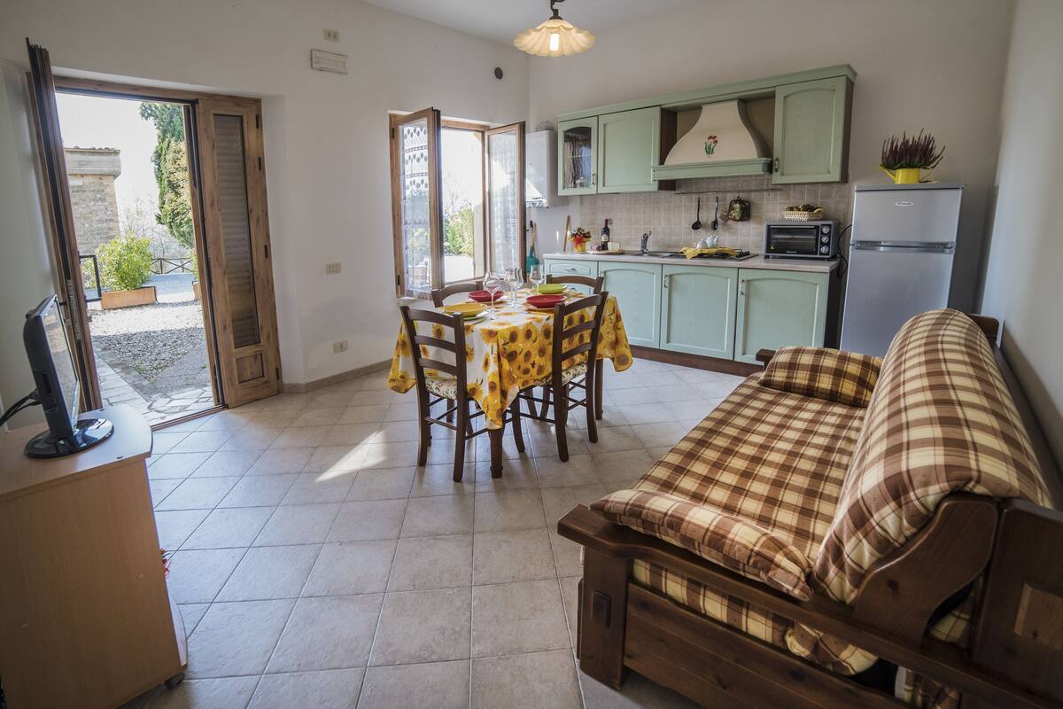 A kitchen with a dining table and chairs, a sofa, and a refrigerator.