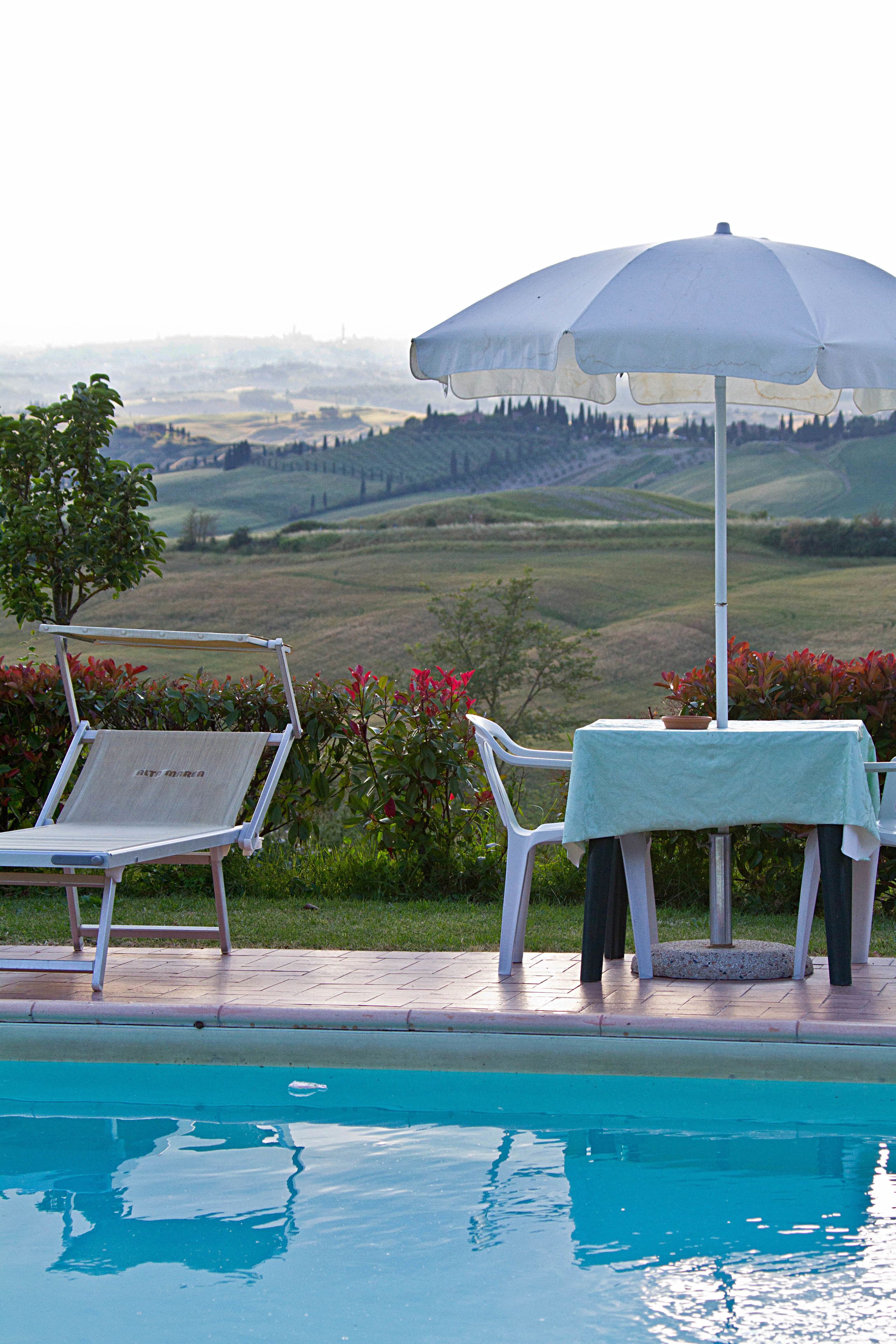 Een buitenzwembad, parasols bij het zwembad en ligstoelen