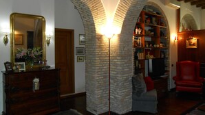 A room with a wooden dresser, a mirror, a bookshelf, and a red armchair. - Pettinary Village (Rome)