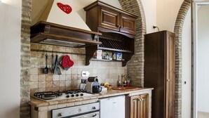 A compact kitchen with a stone backsplash, wooden cabinets, and a built-in oven. - Pettinary Village (Rome)