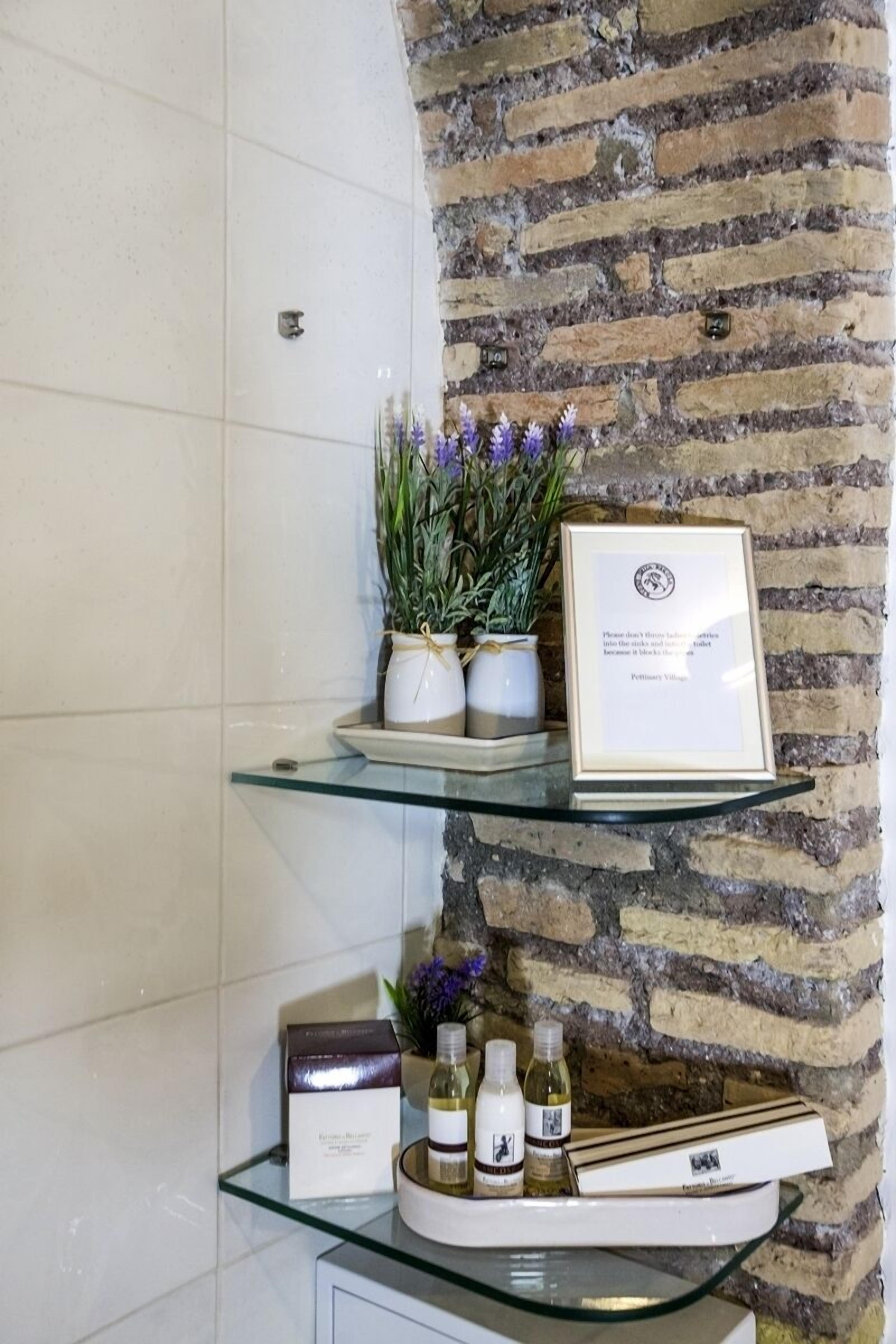 A glass shelf with a framed certificate, a small potted plant, and a bottle of wine.