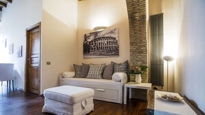 A modern living room with a sofa, ottoman, and a wall-mounted picture of the Colosseum. - Pettinary Village (Rome)