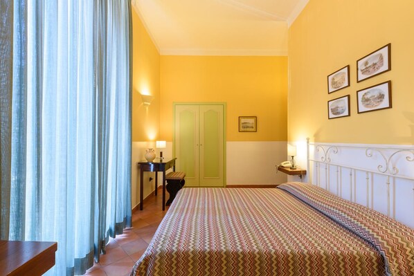 A bedroom with a bed, a desk, a chair, a lamp, and a door. - Mergellina (Naples)