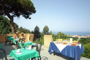 An outdoor dining area with tables set for a meal, overlooking a scenic view.