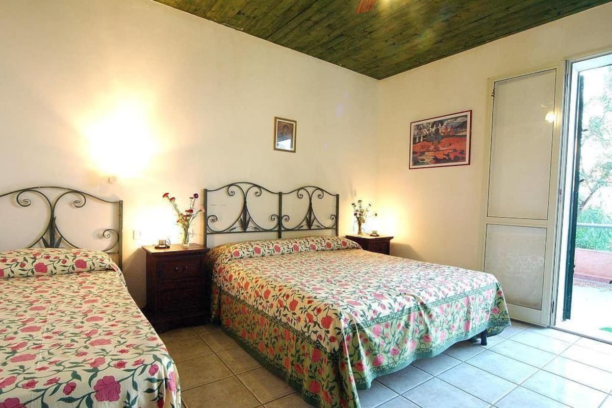 Une chambre avec deux lits, un plafond en bois, une fenêtre et une porte.