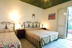A bedroom with two beds, a wooden ceiling, a window, and a door.