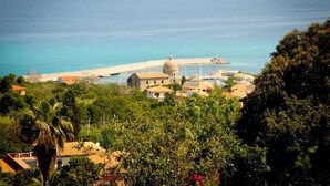 A coastal town with a prominent dome structure, a pier extending into the sea, and residential buildings with red-tiled roofs. - Marchese d'Altavilla (Drapia)
