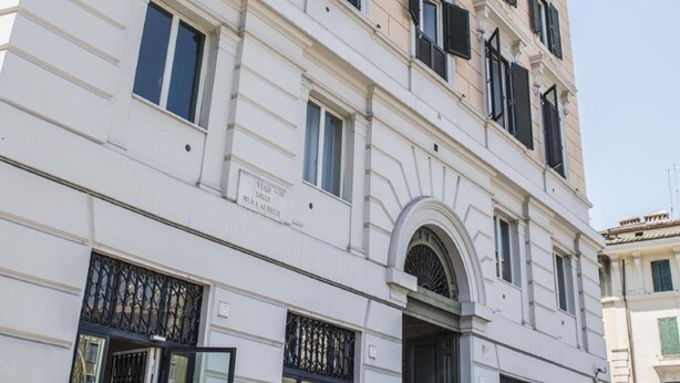 A multi-story building with a classical architectural style, featuring a prominent entrance with a large arched doorway and decorative ironwork. - All'Ombra del Cupolone (Rome)