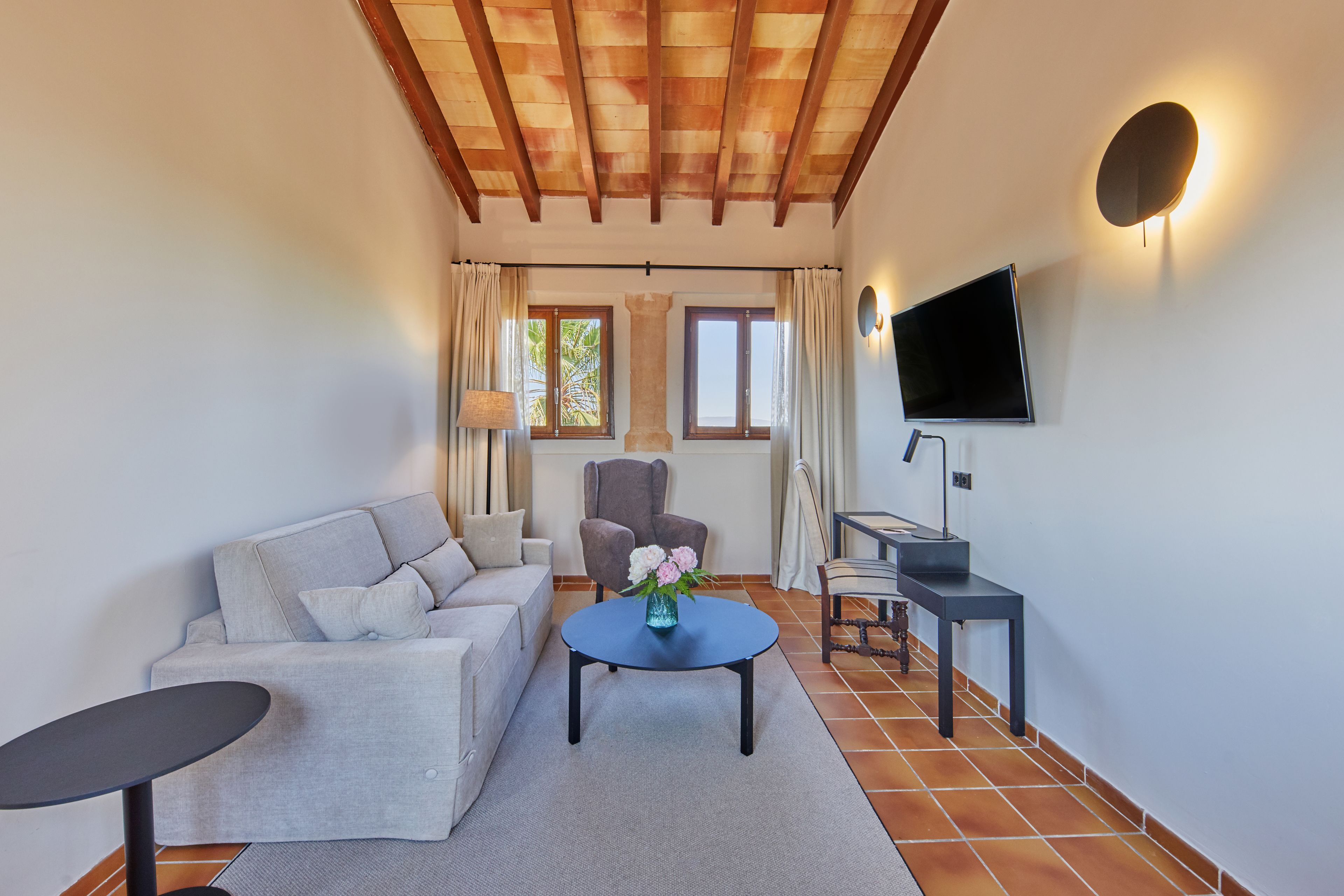 Una sala de estar con sofá, sillón, mesa de centro y televisor.