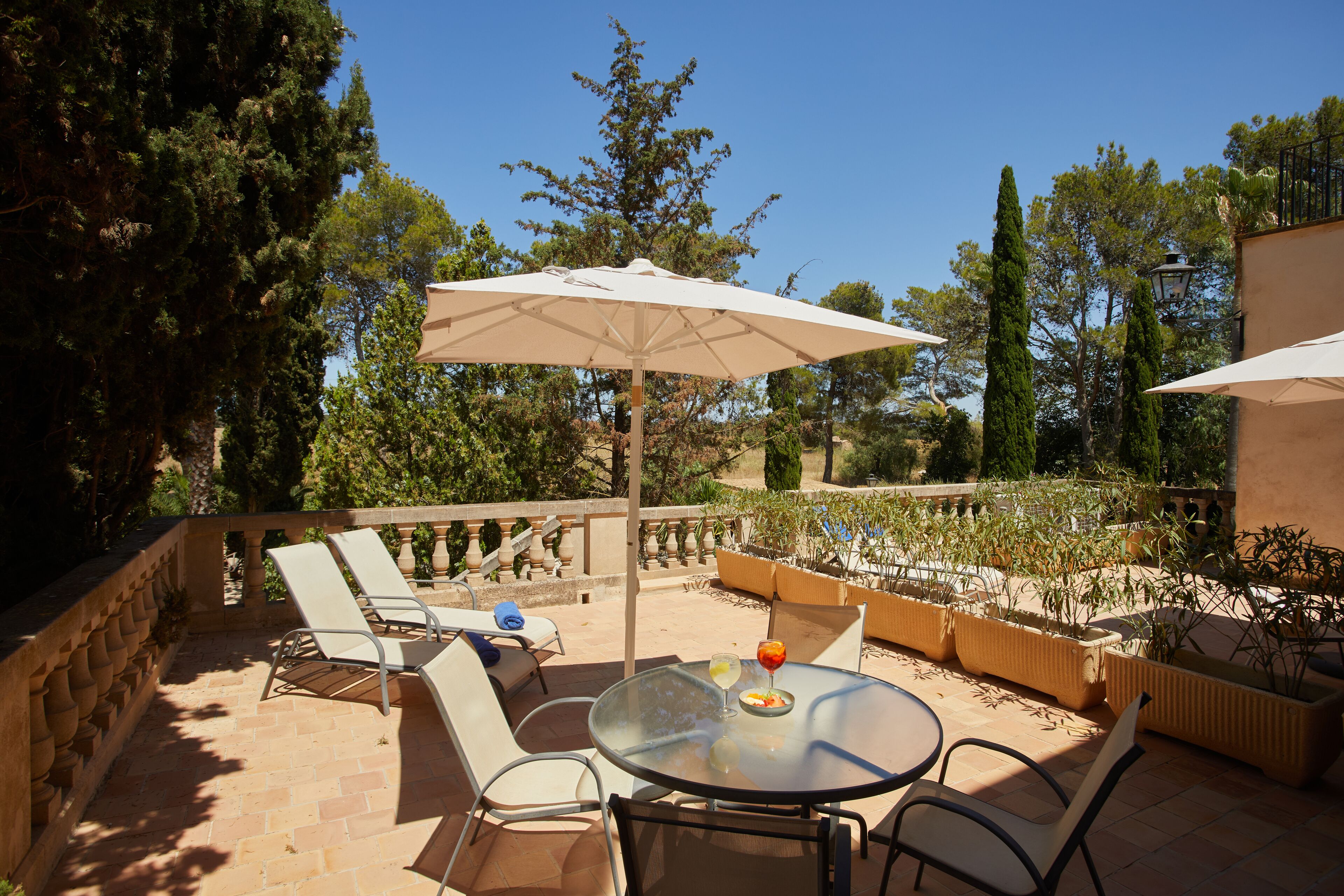 An outdoor patio with a round table, two lounge chairs, and a large umbrella.
