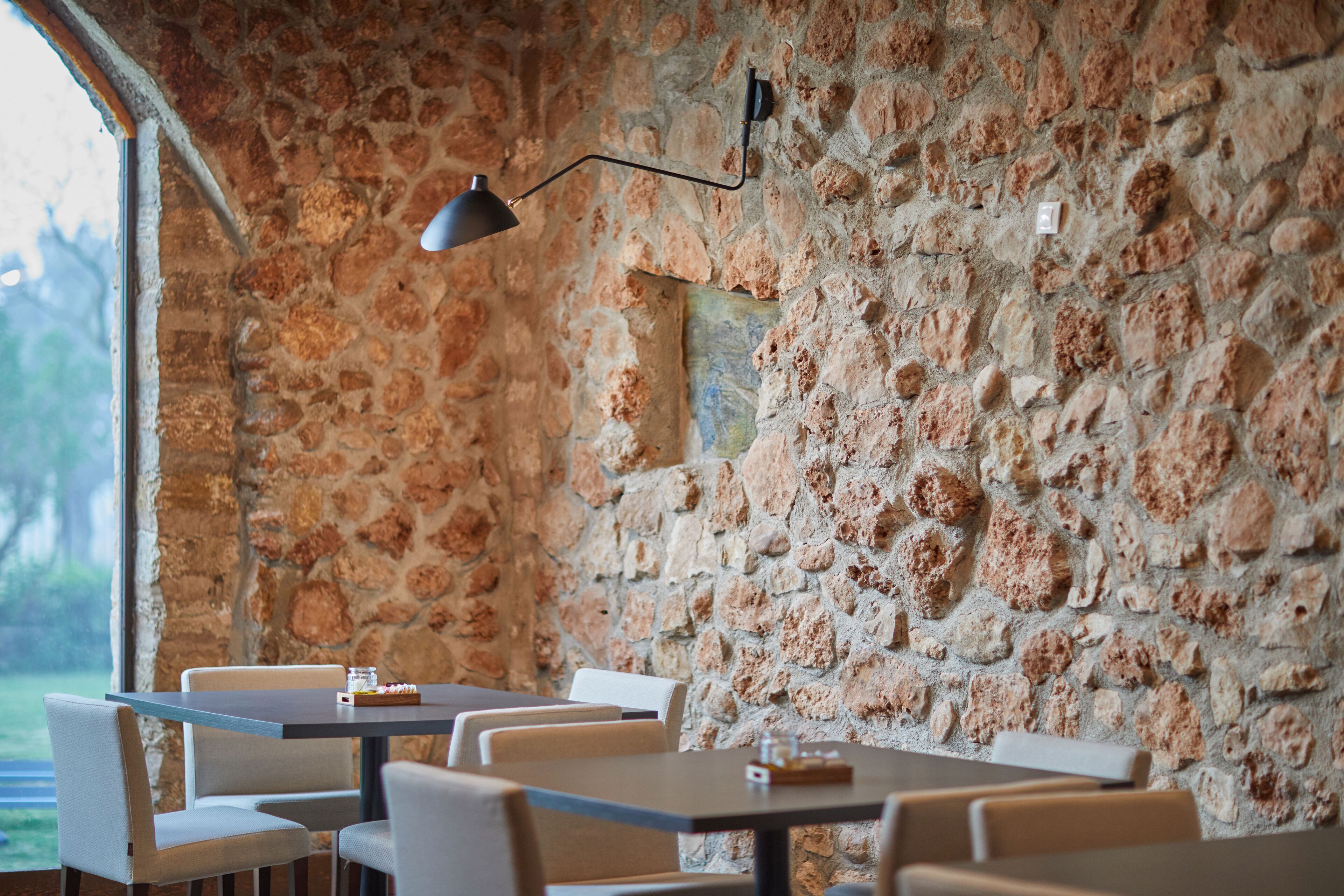 A restaurant with stone walls, tables, and chairs.