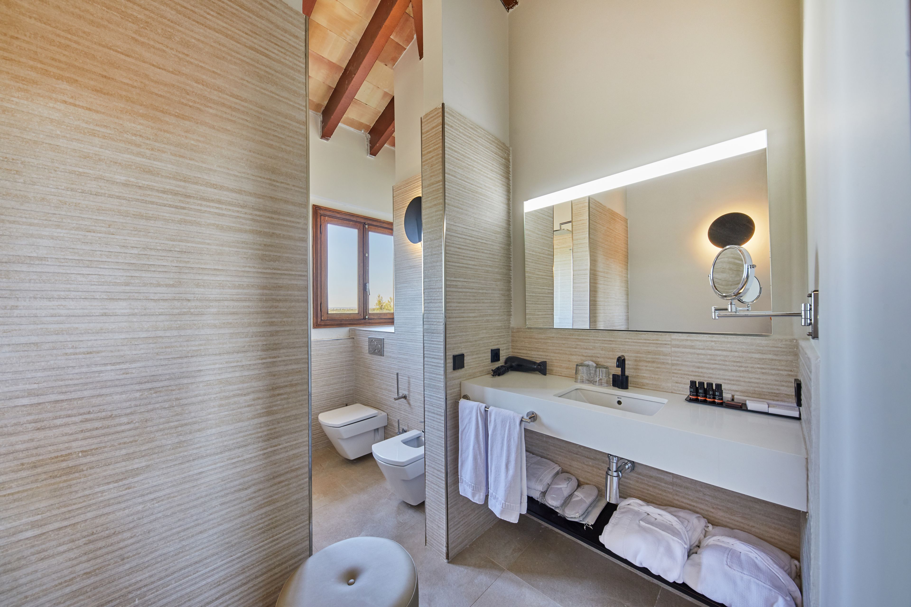 Un baño moderno con un espejo grande, sanitarios blancos y un perchero para toallas.