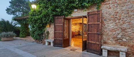 A stone building with wooden doors and a lit lamp outside.
