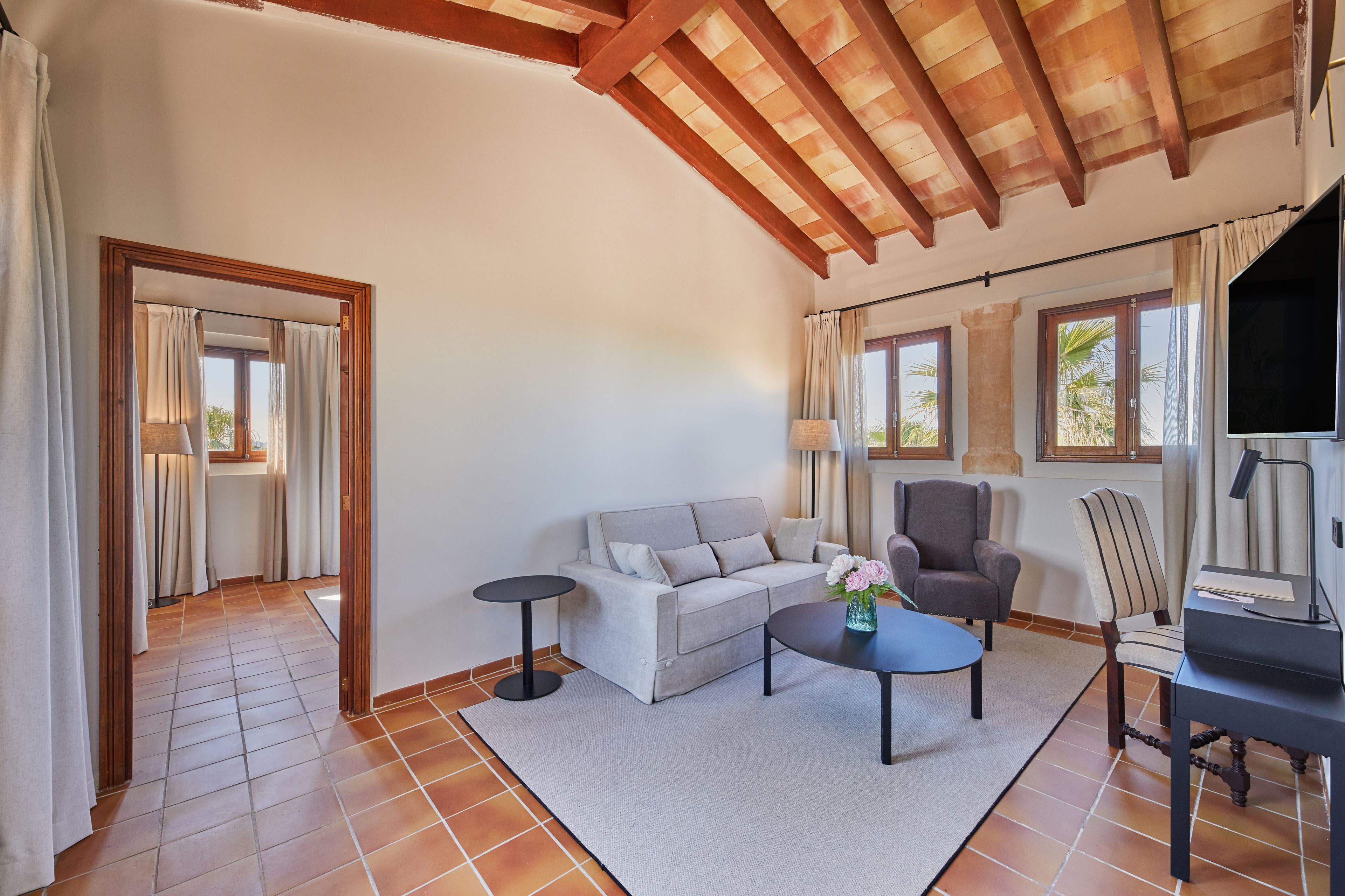 Un salon comprenant un canapé, des fauteuils, une table basse et un téléviseur.